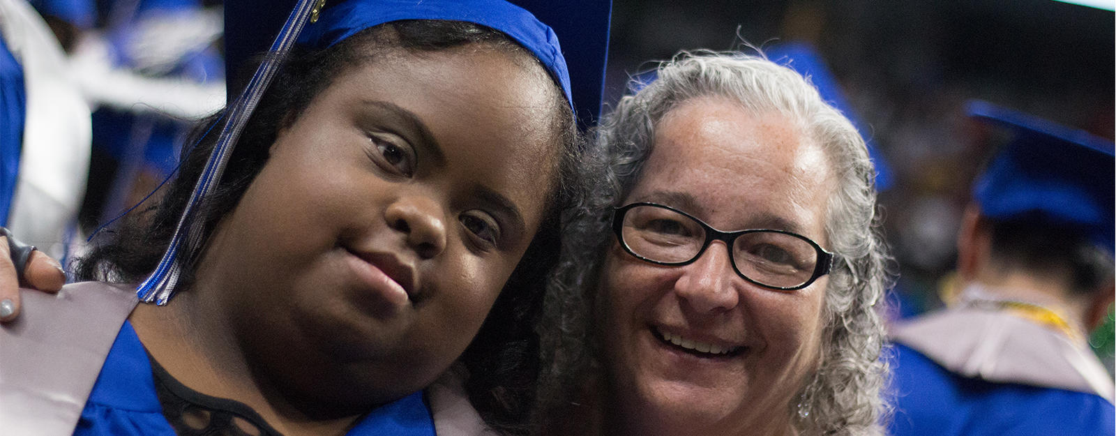 Special Education student smiling for a picture with a staff member during graduation.