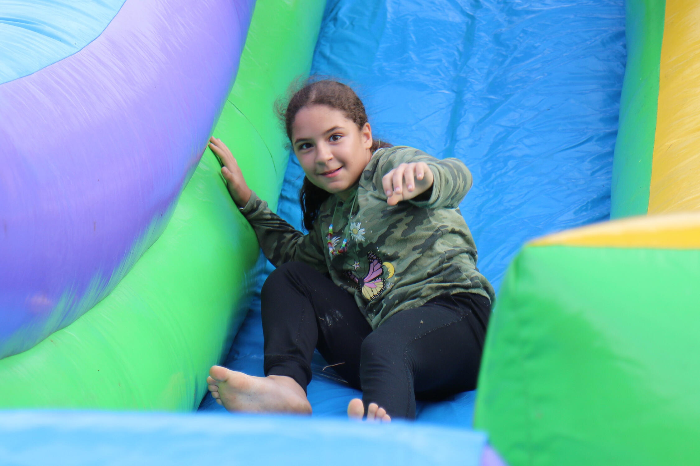 Student smiling while sliding down a large inflatable slide