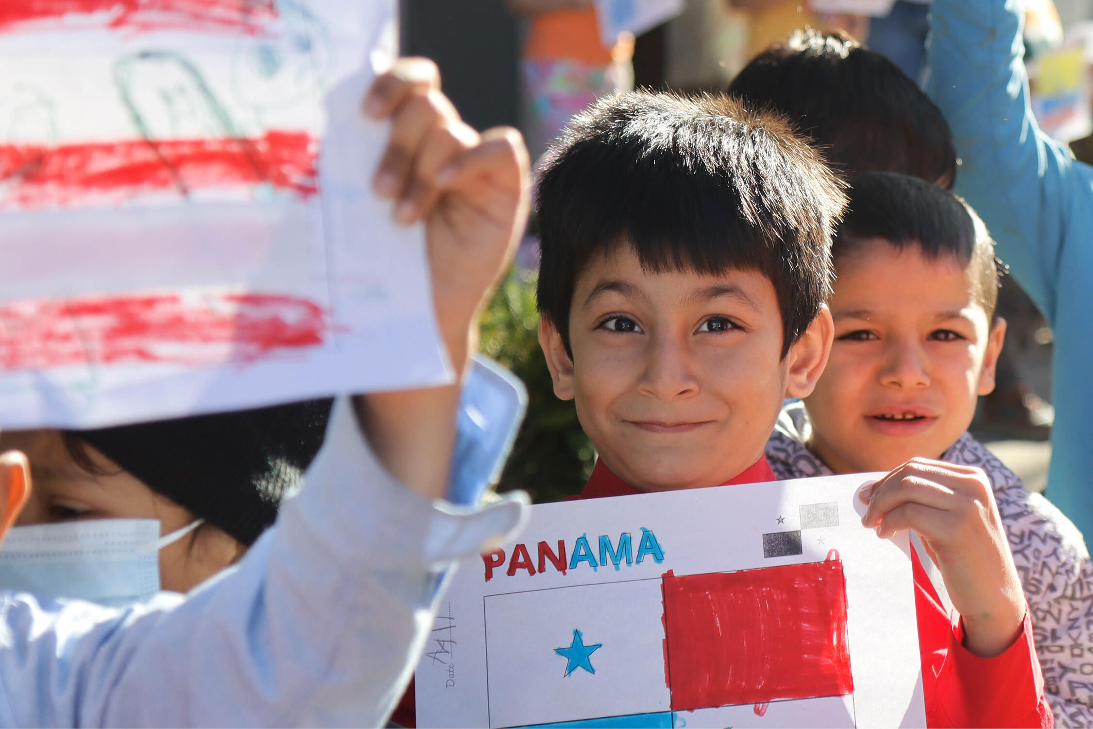 Student smiling and holding up a drawing of the Panamanian flag