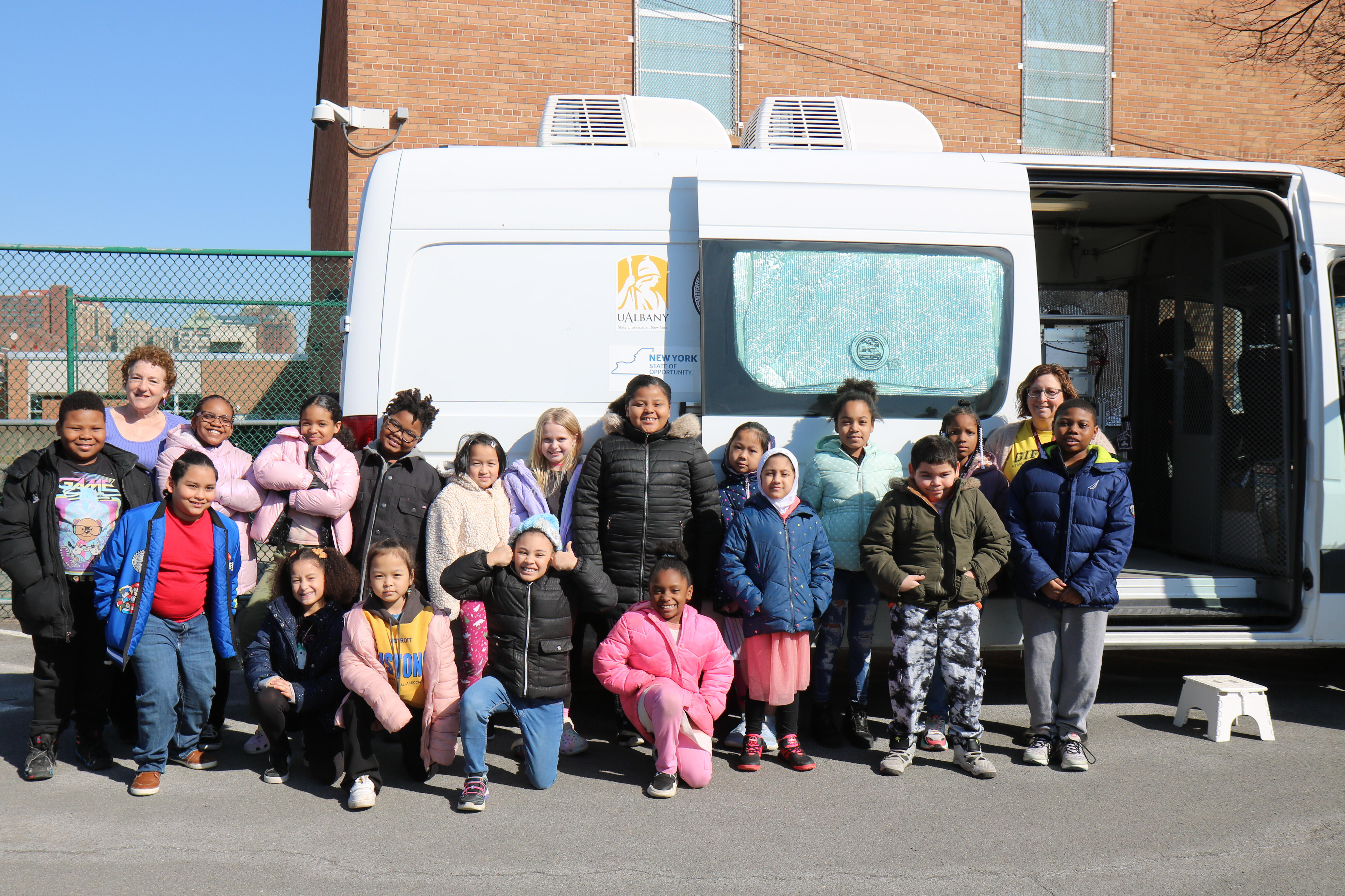 Students posing for a group photo in front of the air quality monitoring van