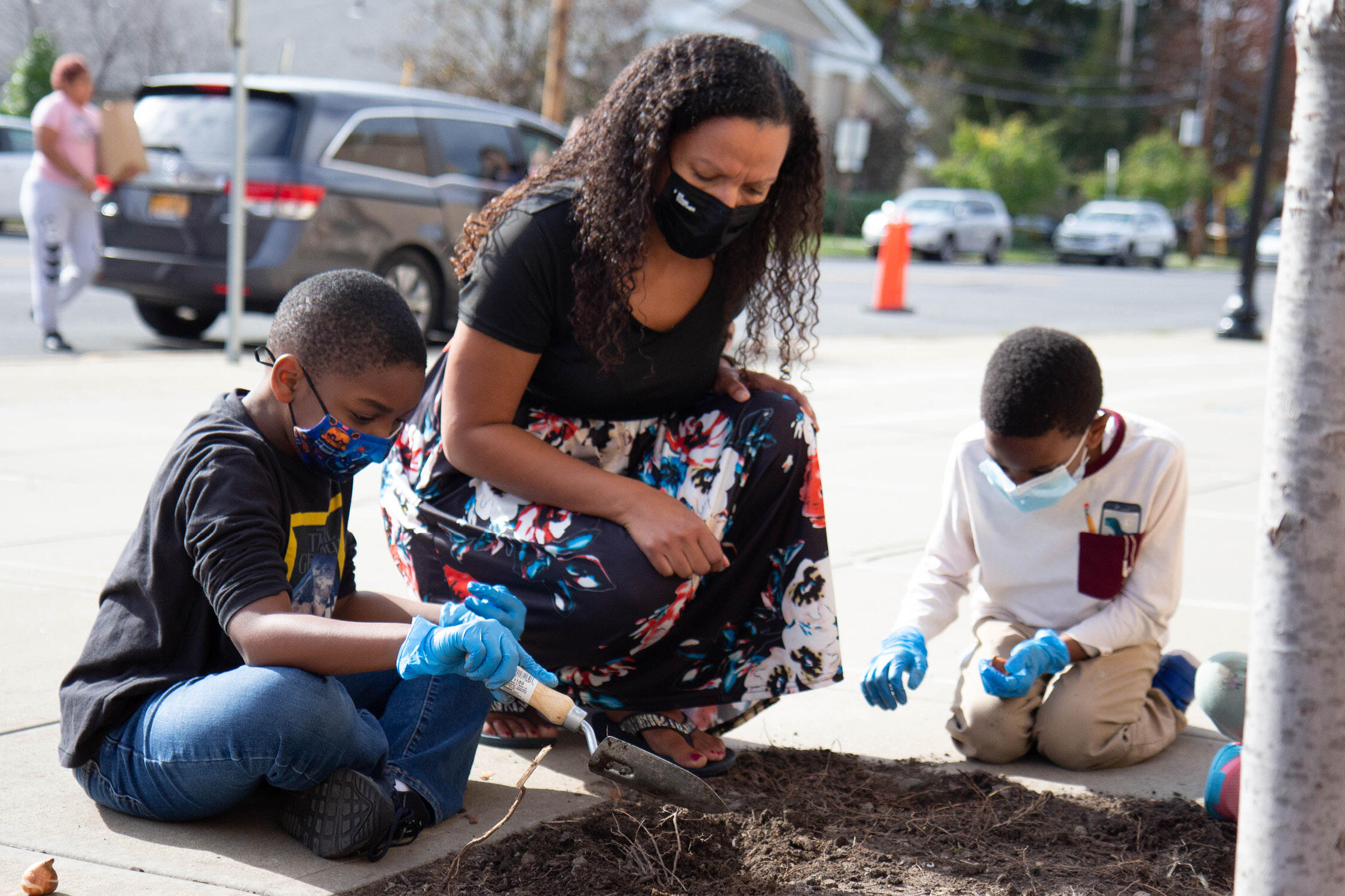 Two students and their teacher planting flower bulbs
