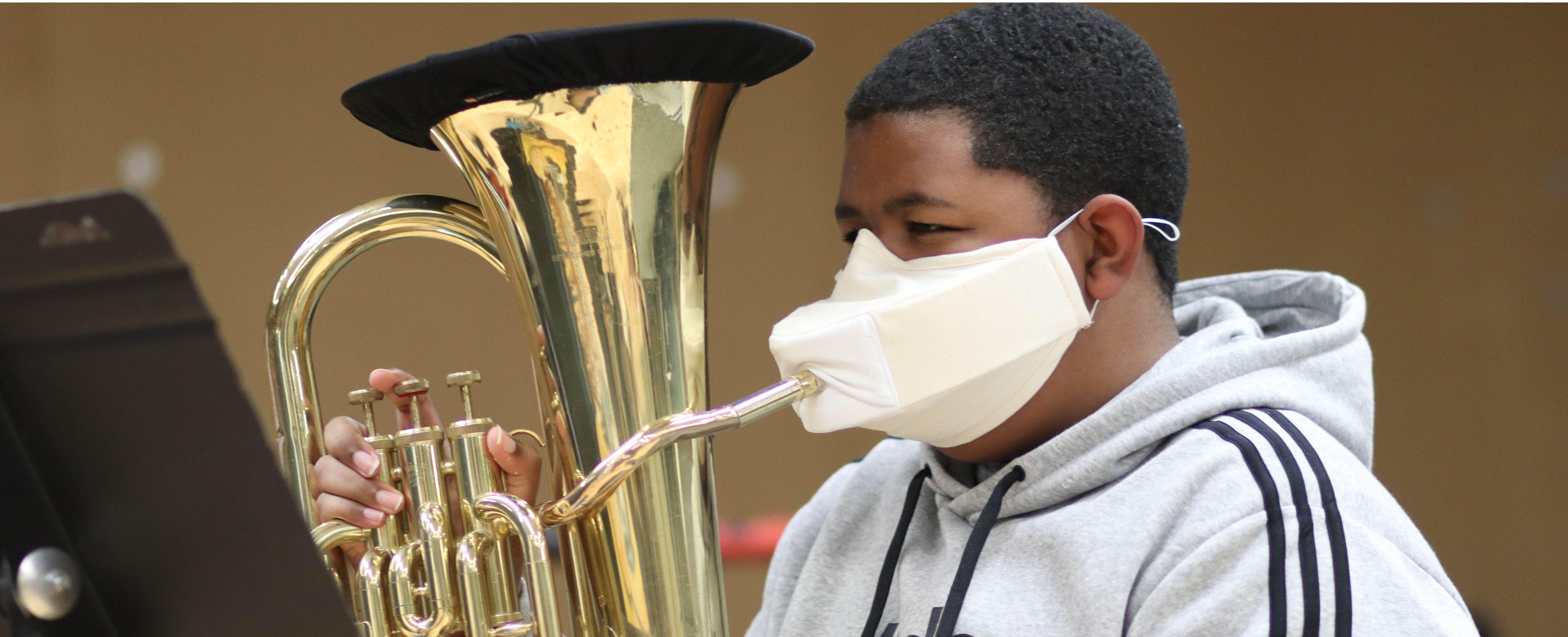 Student wearing a mask holding an instrument.