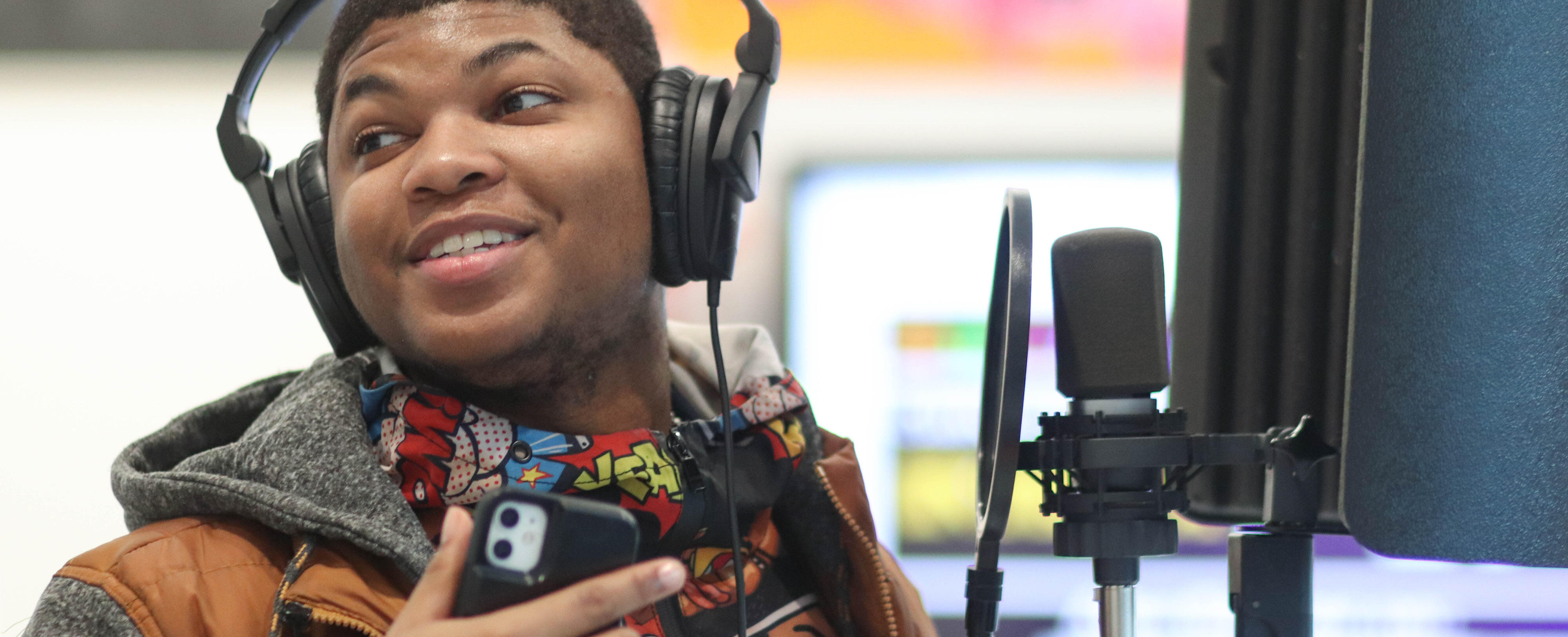 Student wearing headphones and smiling while recording a song 