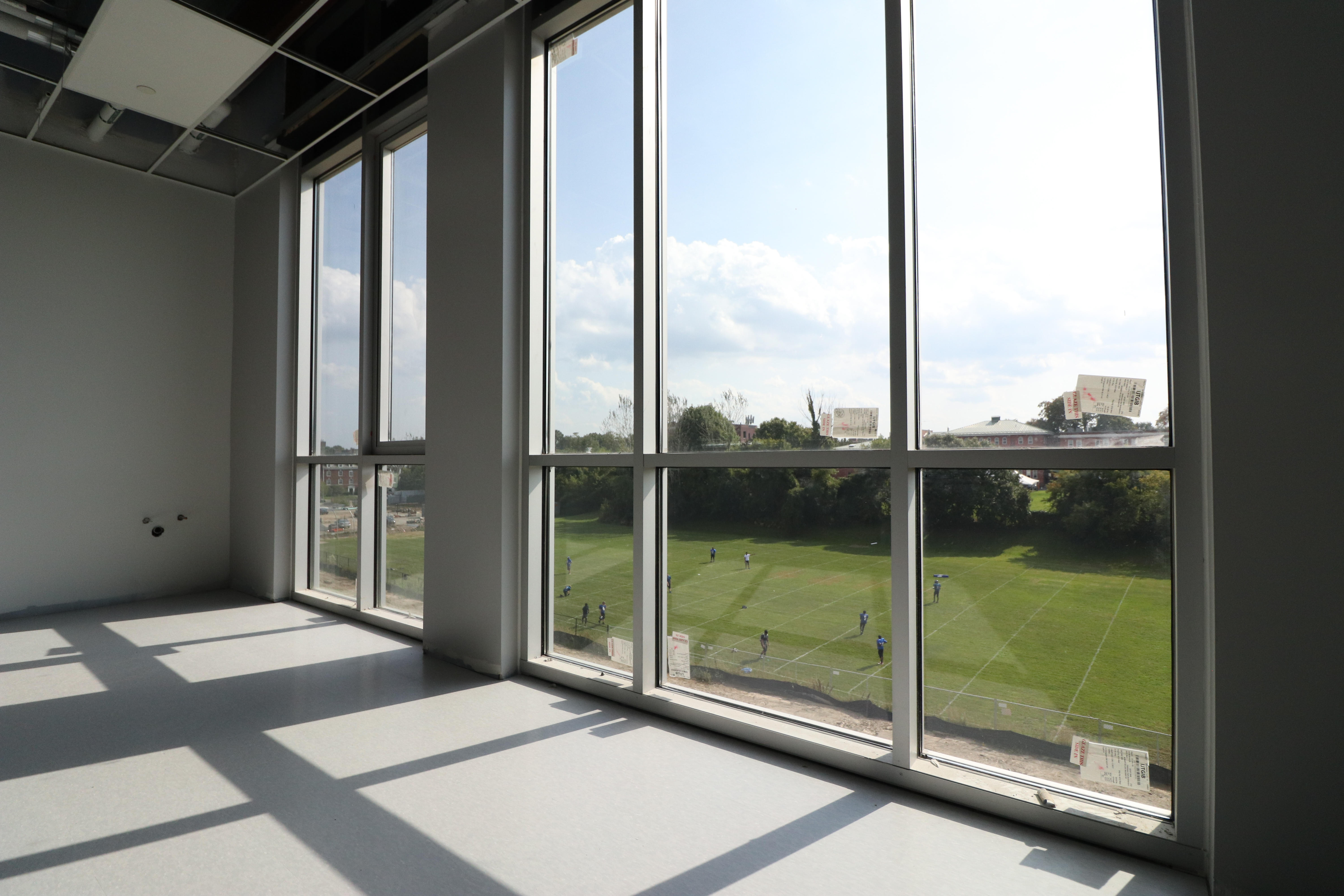 Interior of a classroom in the new Phase I academic building, with large, sun-filled windows facing out to the field