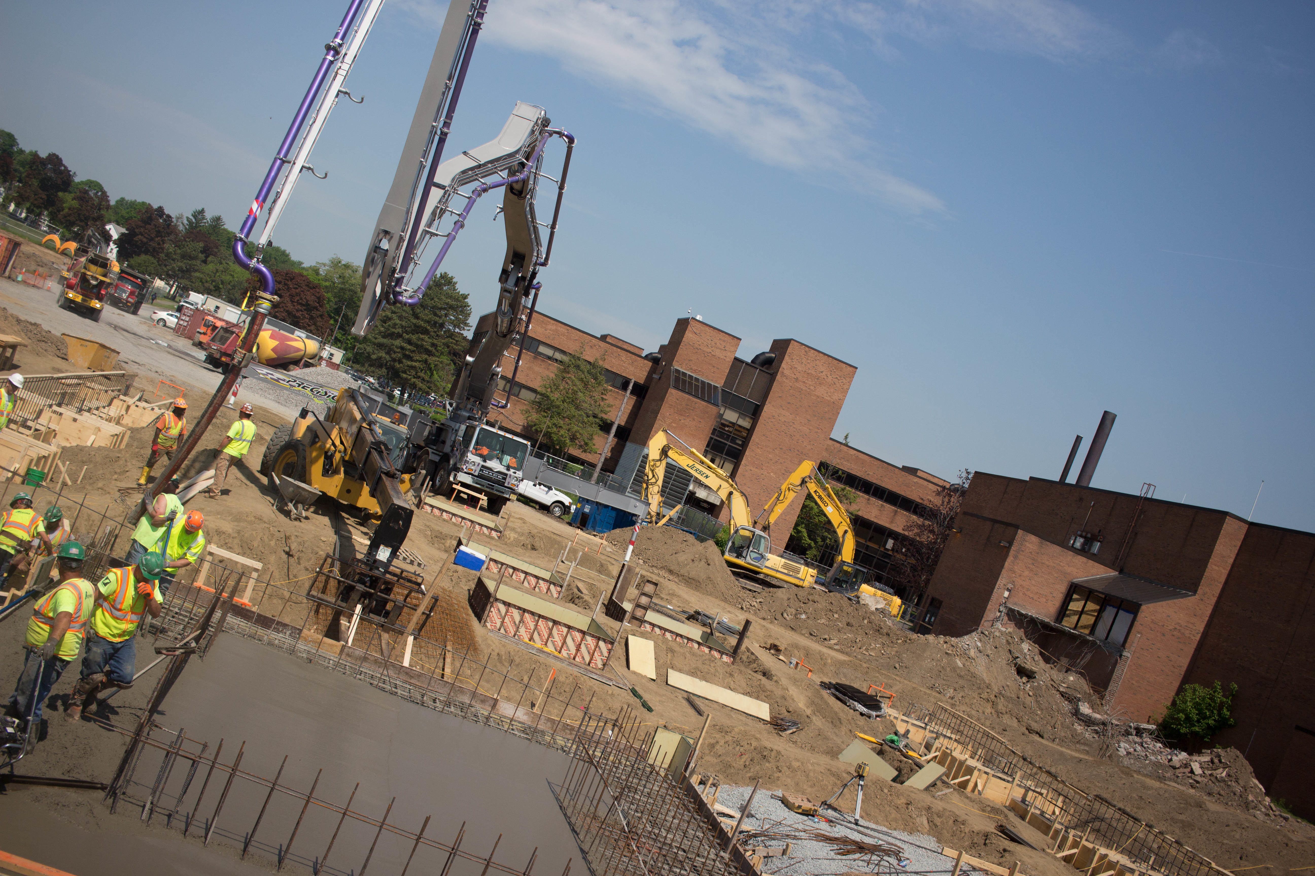View of the construction site with the foundation of the new academic building in the foreground, and the existing Albany High in the rear.