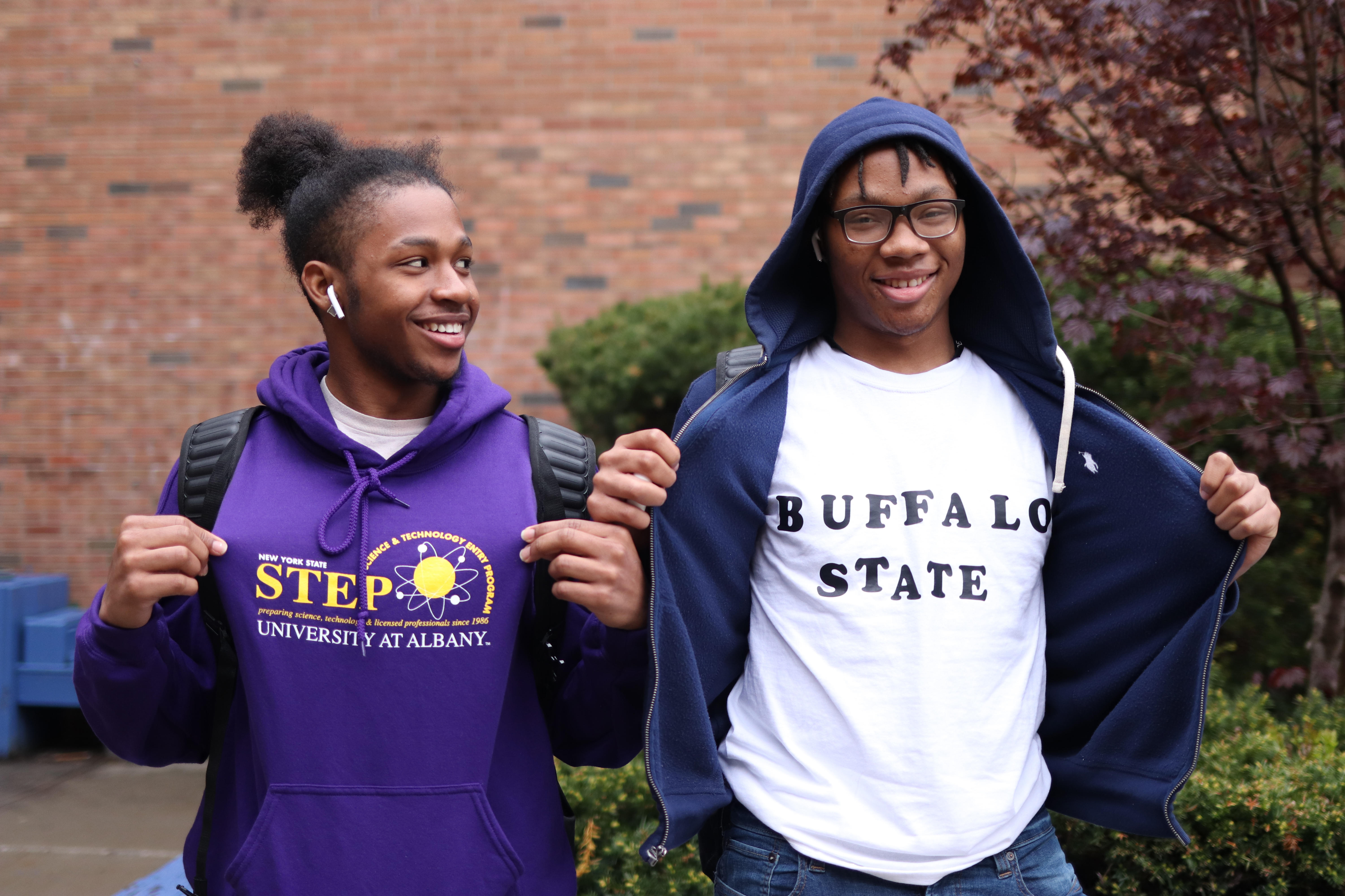 Two students showing off their college t-shirts.