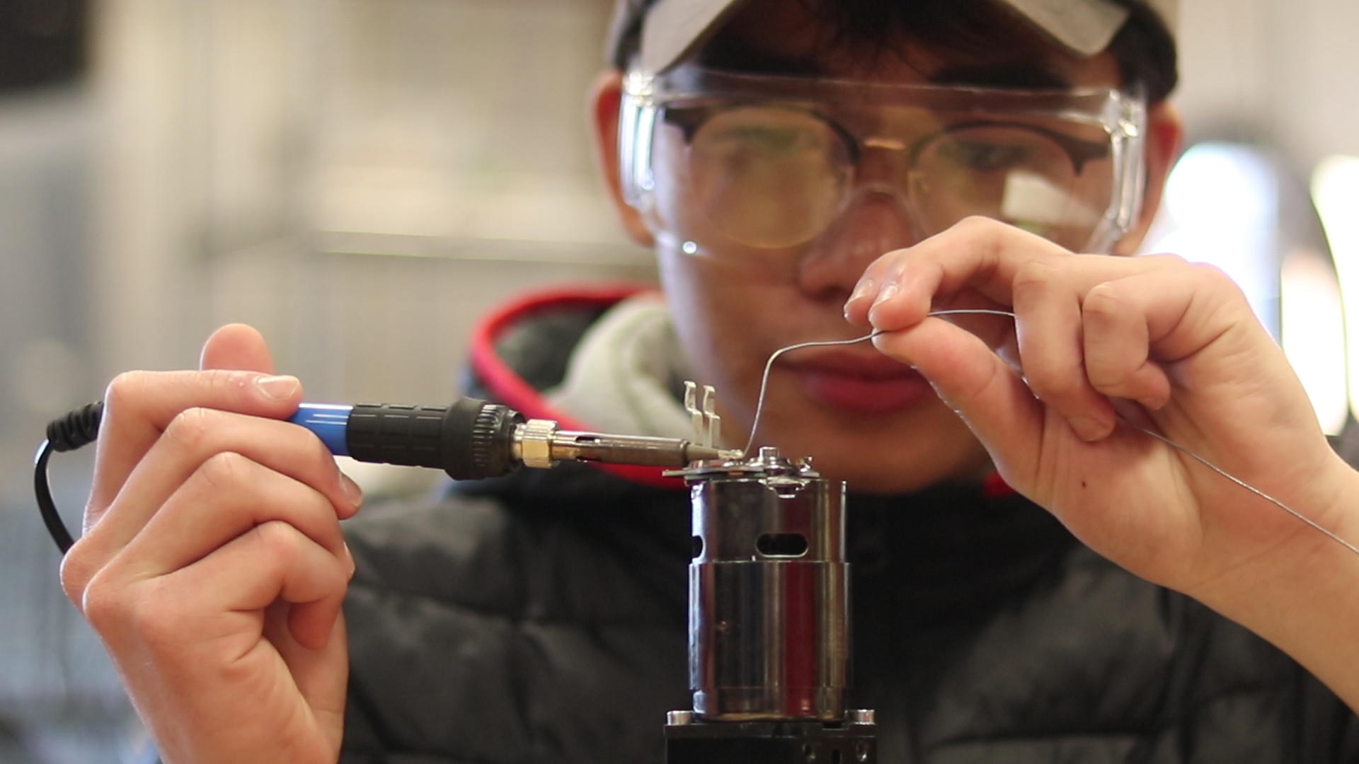 Student soldering wires in Robotics Club