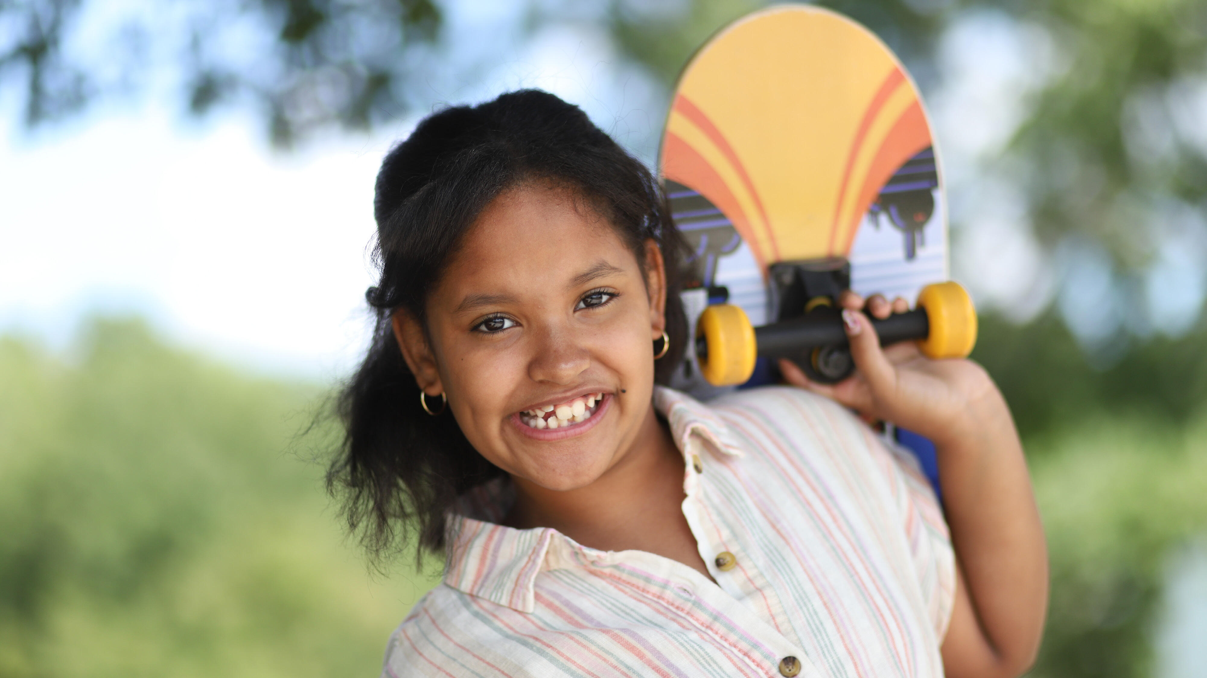Student smiling while holding a skateboard