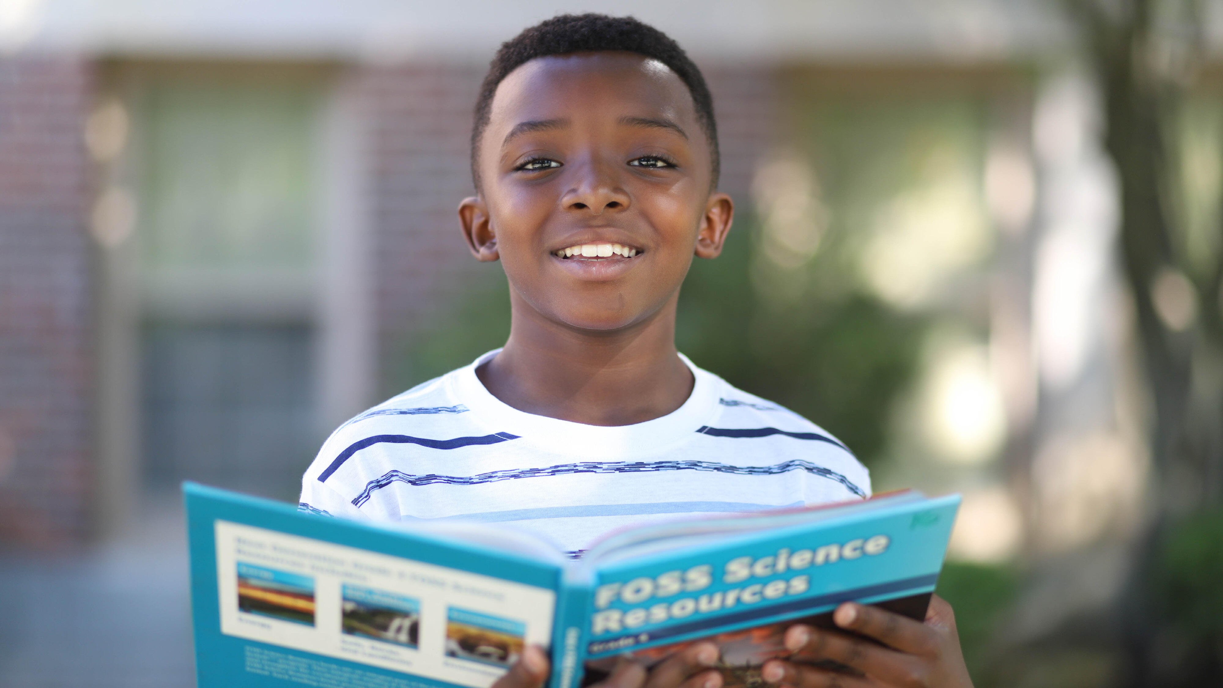 Student smiling and holding a science textbook