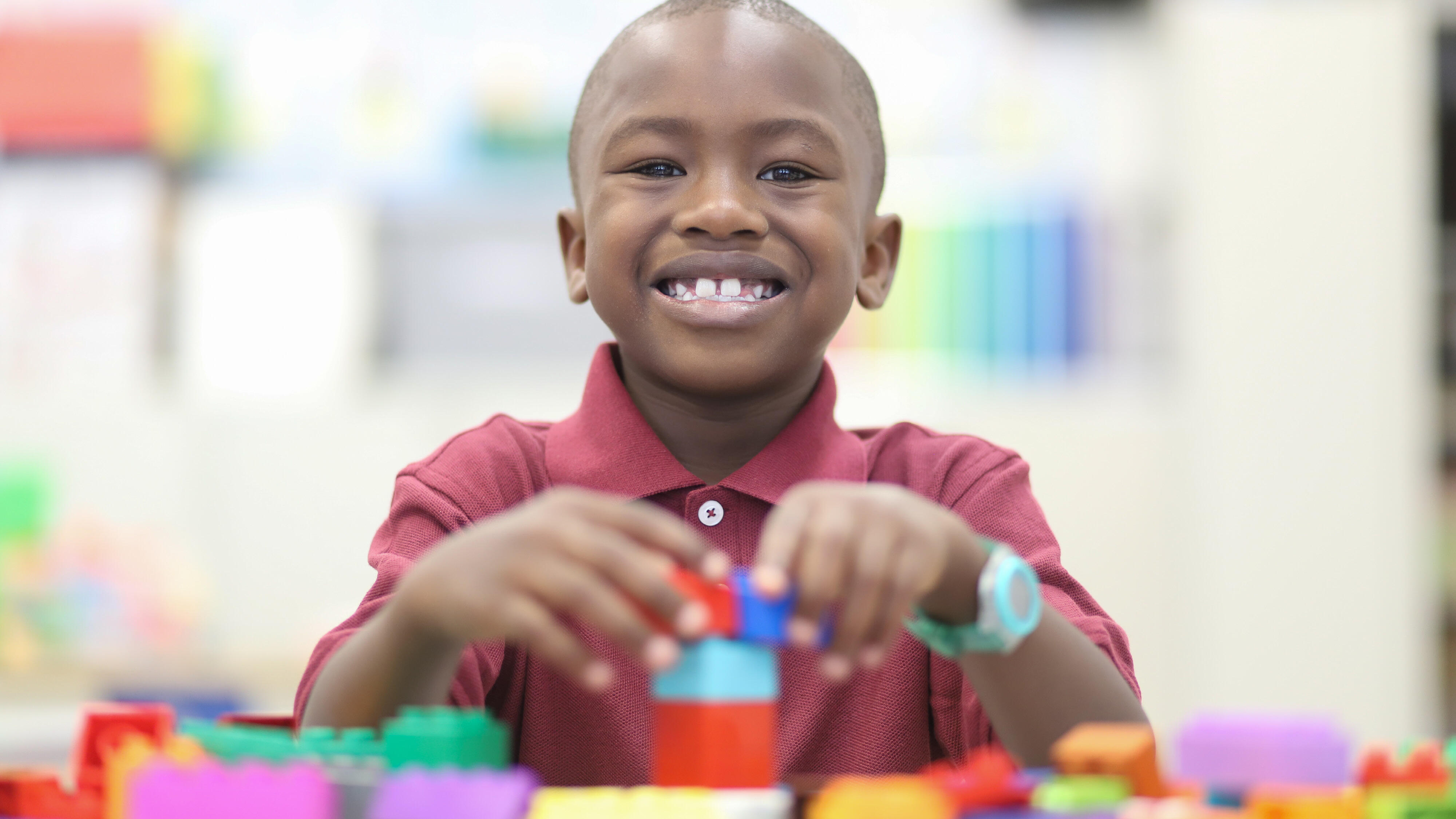 Student smiling and building with blocks