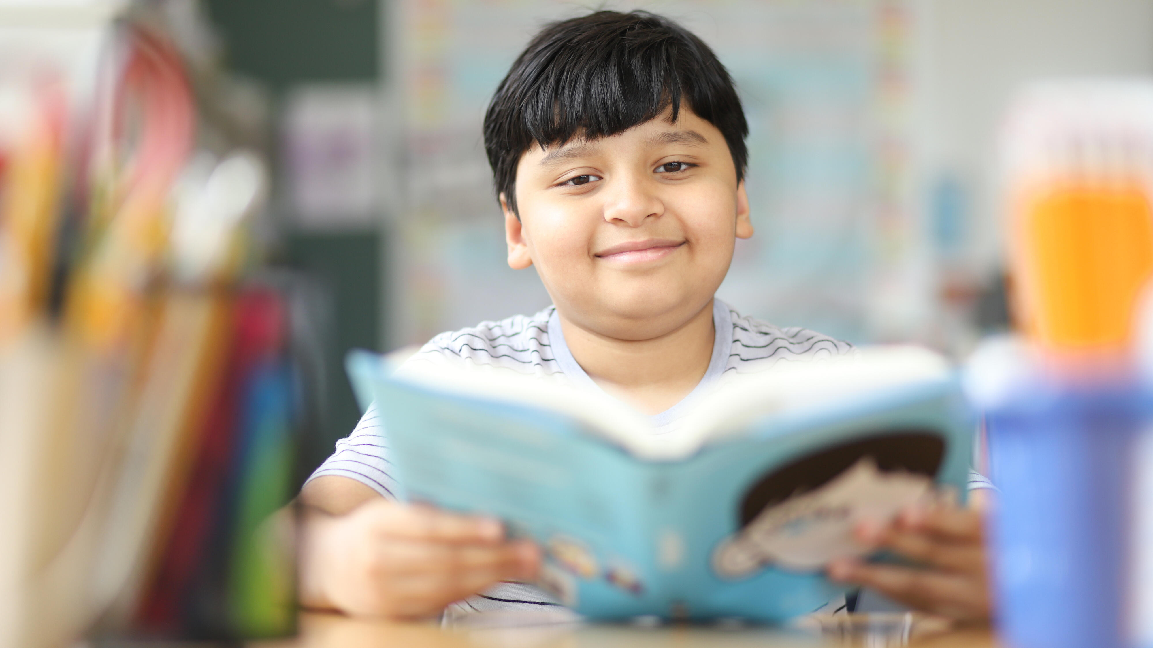 Student smiling while reading a book