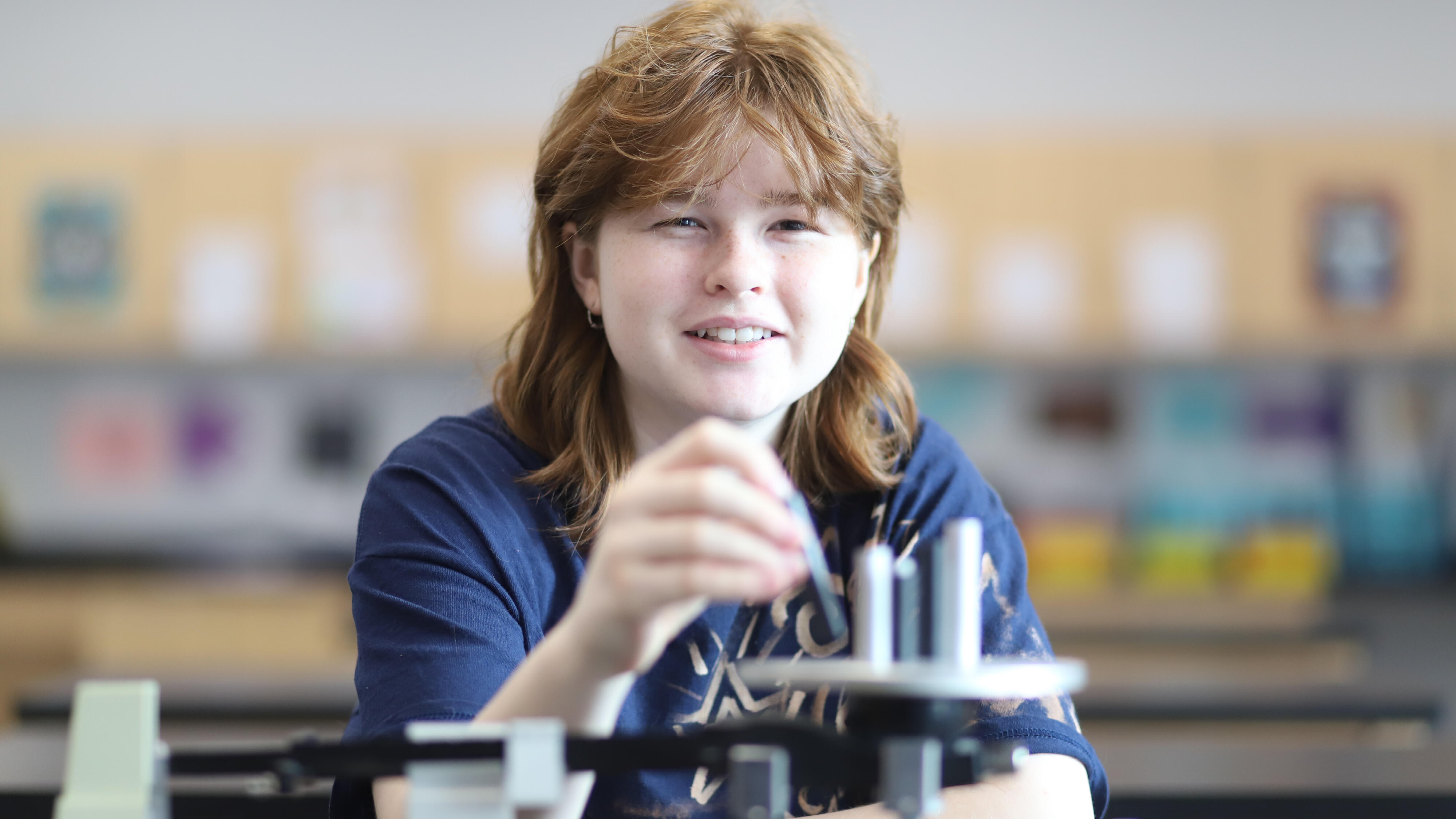 Student smiling while using a triple-beam balance