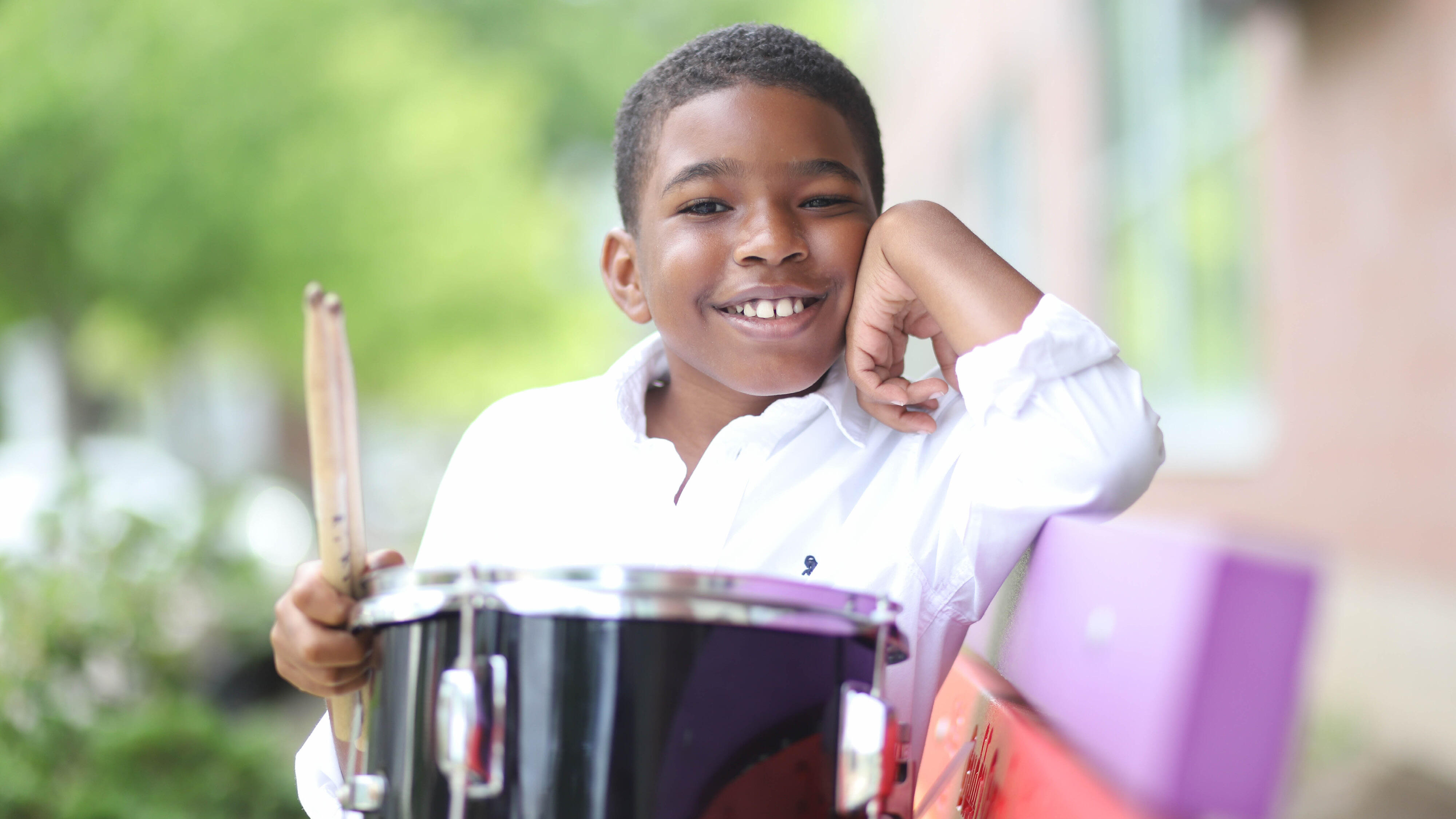 Student smiling and holding a snare drum on a bench
