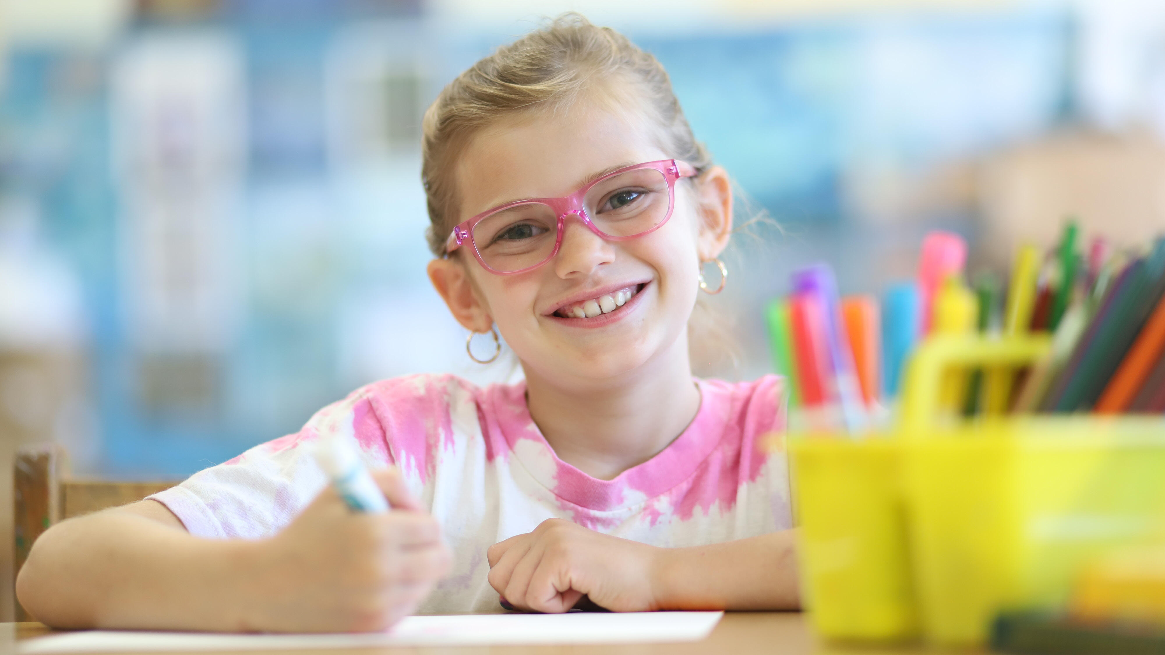 Student smiling while drawing with markers